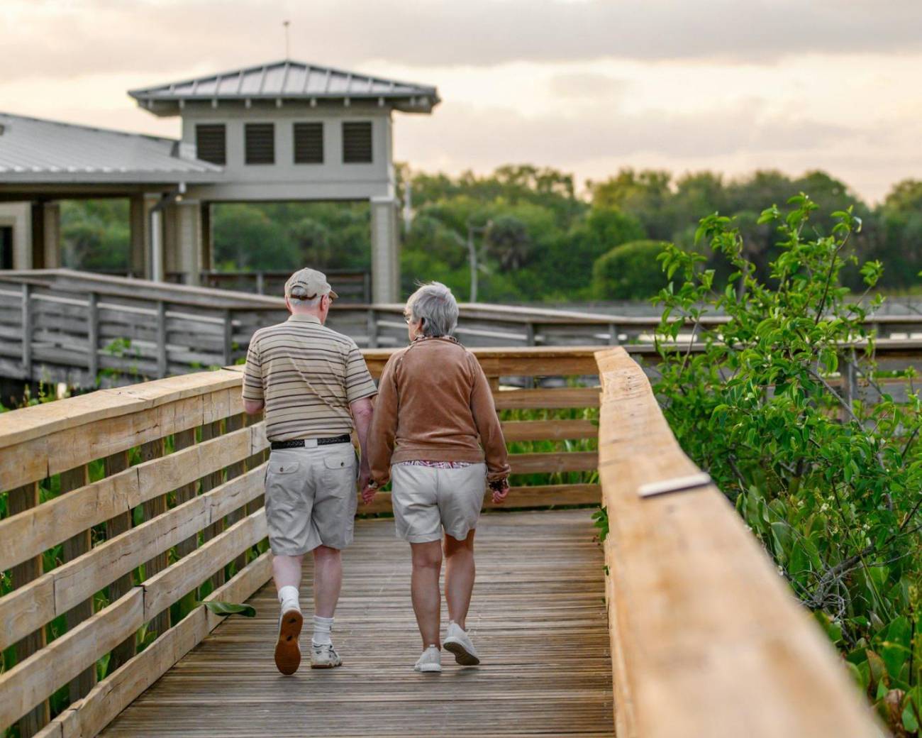 Two residents walking together along a boardwalk outside a senior living community